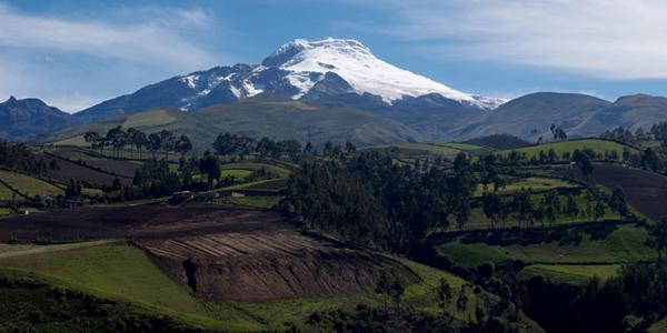 A dormant volcano lies sleepily behind lush Ecuadorian countryside.