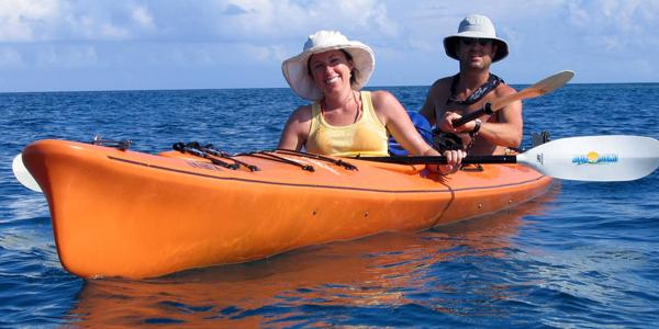 A couple kayak through waters off the coast of Belize