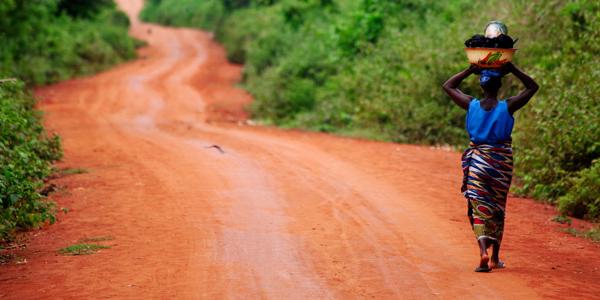 Woman walking down a red path in Benin.