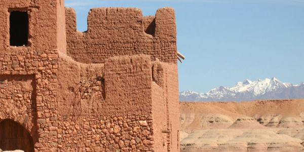 Ancient Moroccan building in front of mountain range.