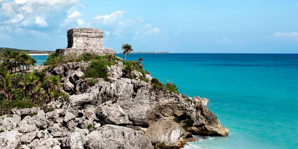 A traditional stone building sits atop the Mexican coastline
