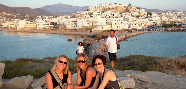 Travellers pose for a photo in front of a picture-perfect Greek village