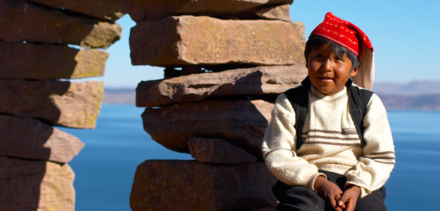 A Bolivian child smiling in front of water