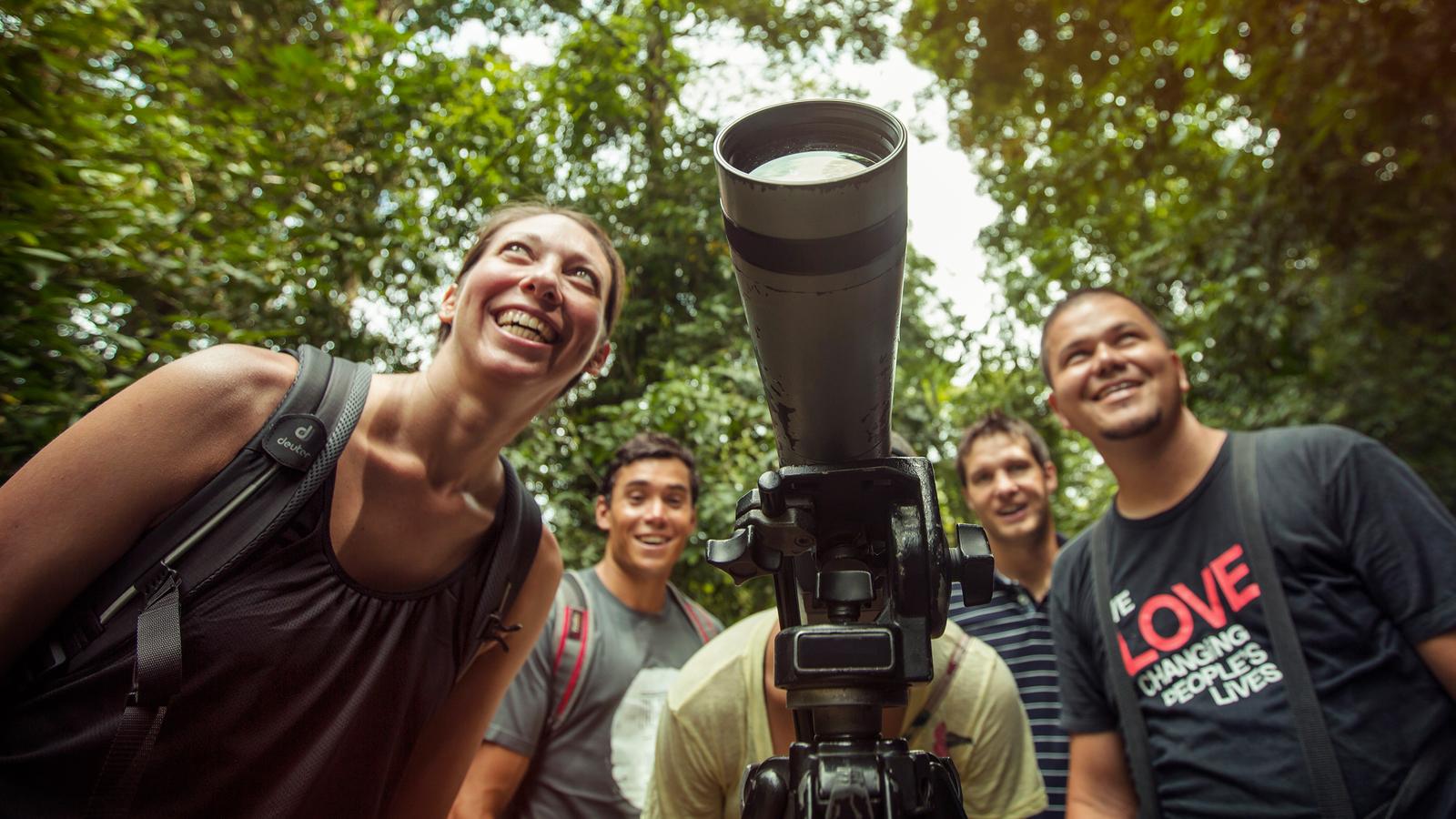 A group of travellers watch wildlife through a large zoom lens in Costa Rica