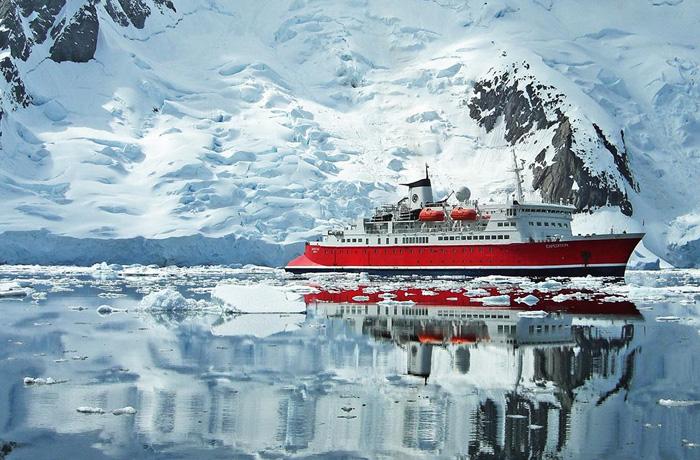 The G Expedition ship sailing past a snowy mountain in Antarctica