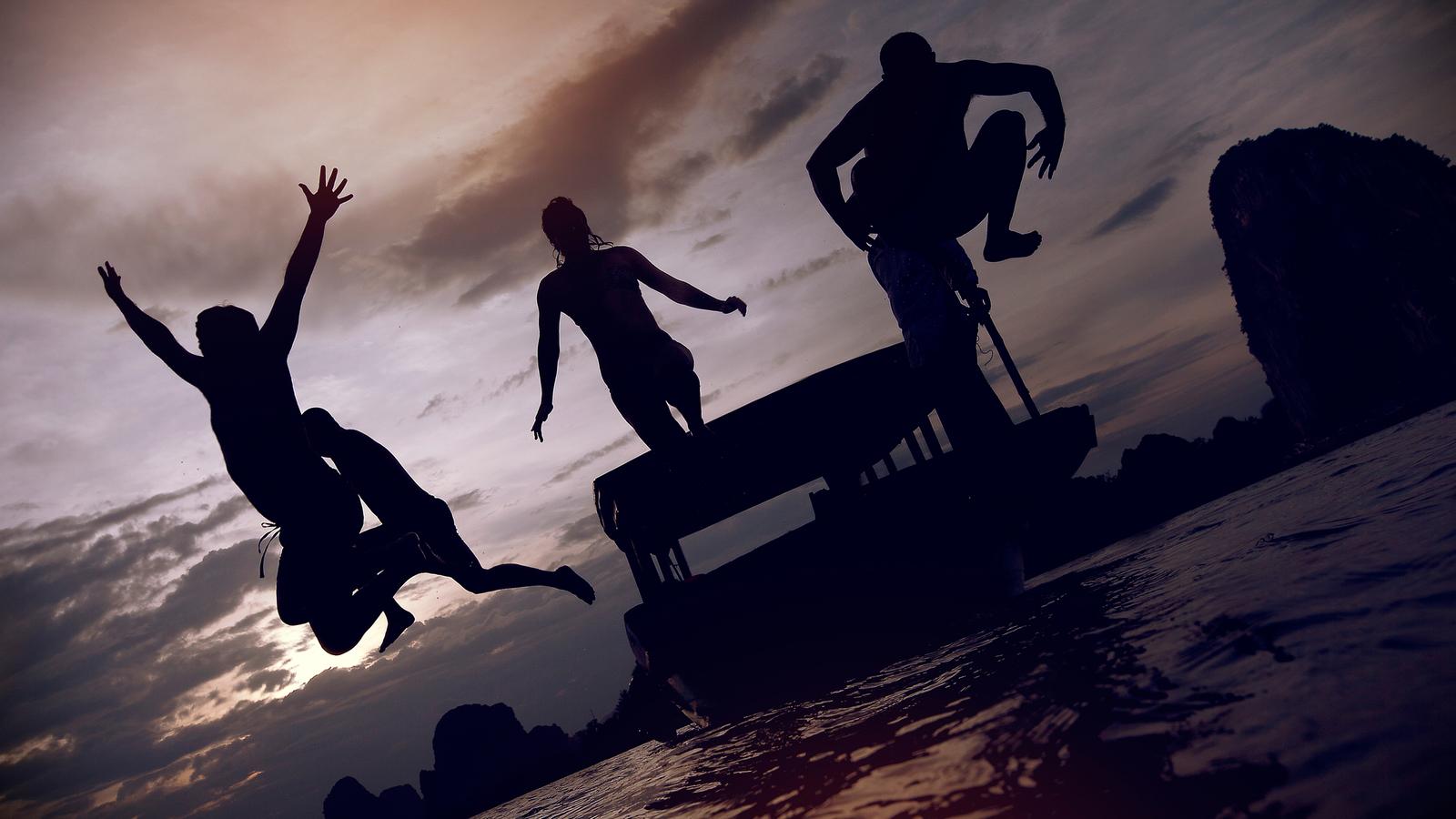 Group of travellers jumping into Halong Bay during sunset in Vietnam