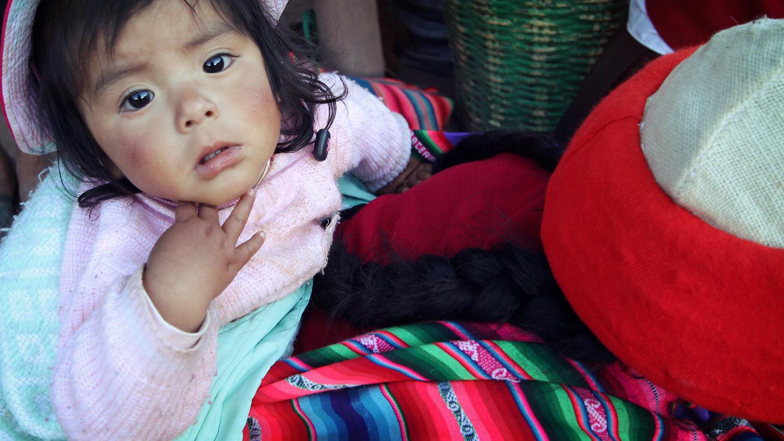A small child looks up at the camera in Cusco, Peru