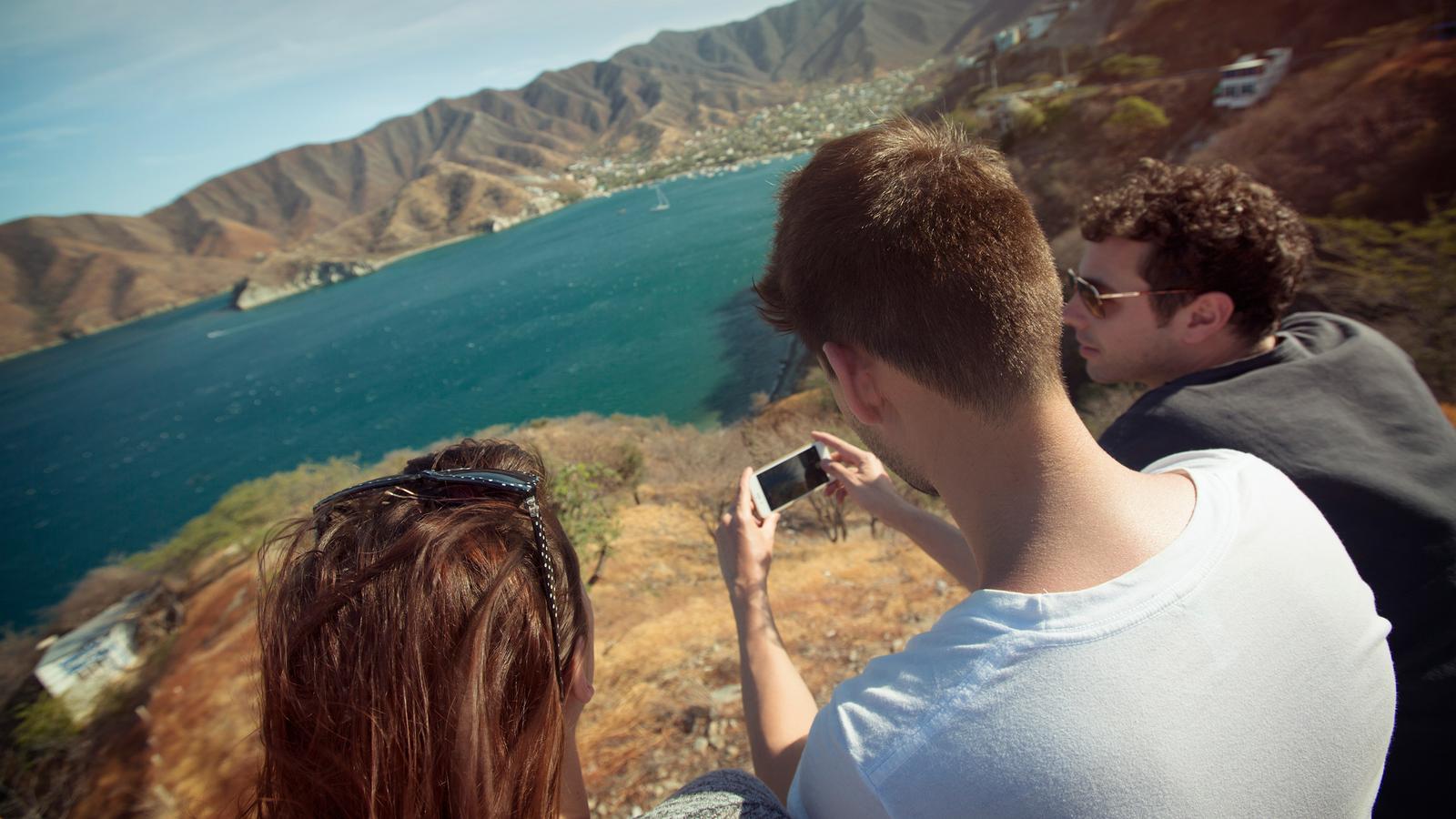 Travellers taking photos of the lake and mountains in Taganga, Colombia