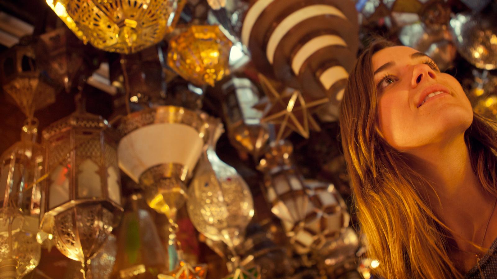 Young female traveller marvels at the beautiful lanterns hanging in the grand bazaar in Marrakech, Morocco
