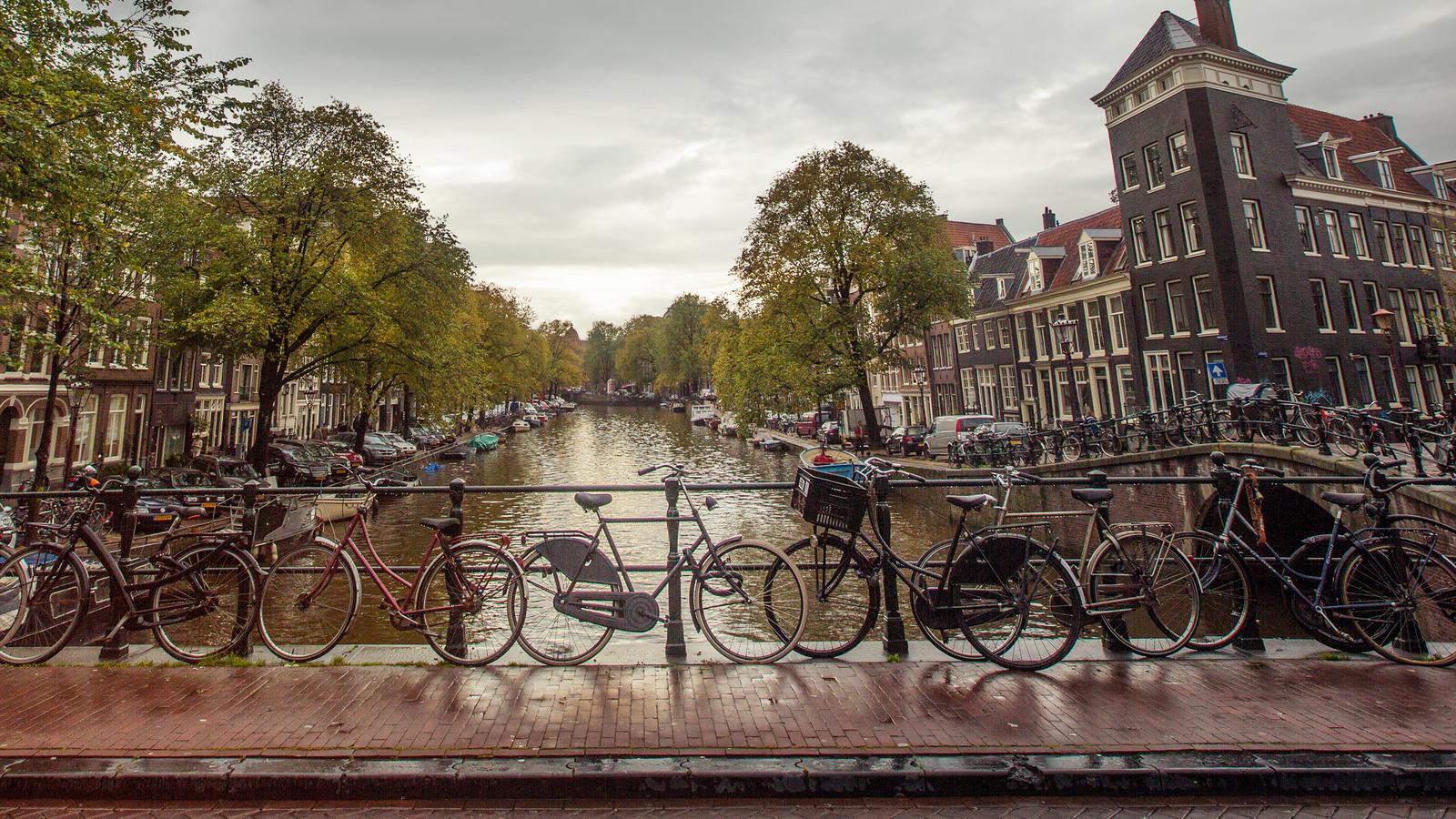 Bikes standing atop a bridge leading to a canal in Amsterdam, Netherlands