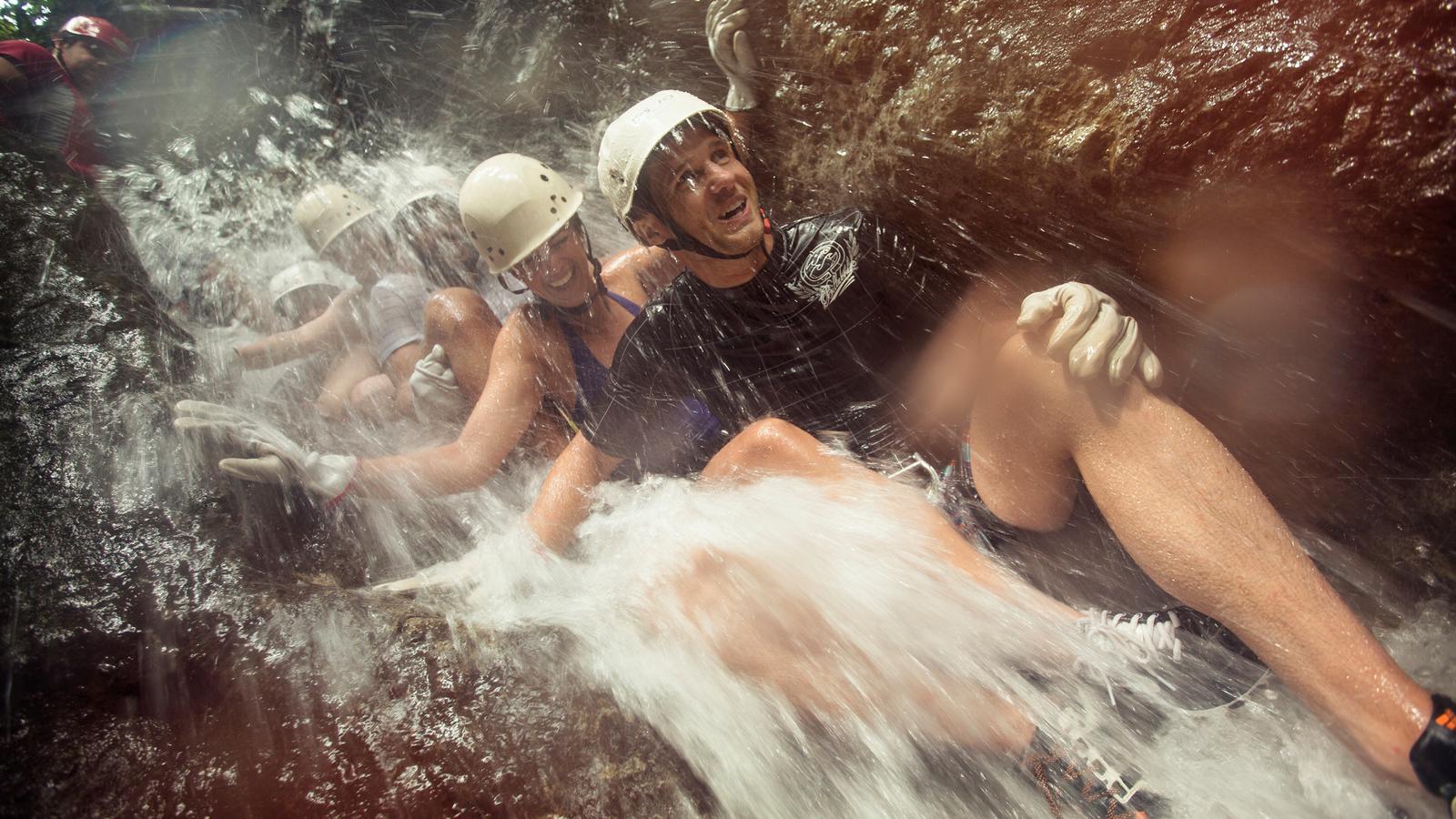 A group of travellers canyoneering down a waterfall in Costa Rica