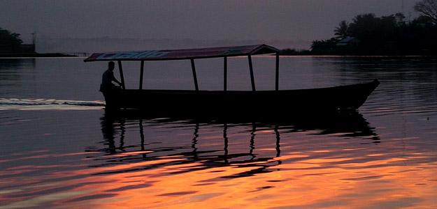 A man steers his boat down the Rio Dulce at dawn