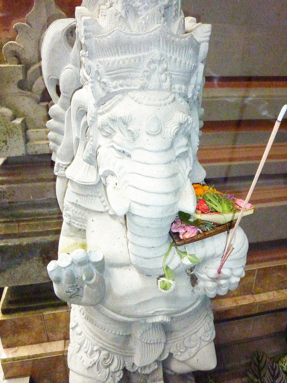 A canang sari offering tucked into a Ganesh statue.